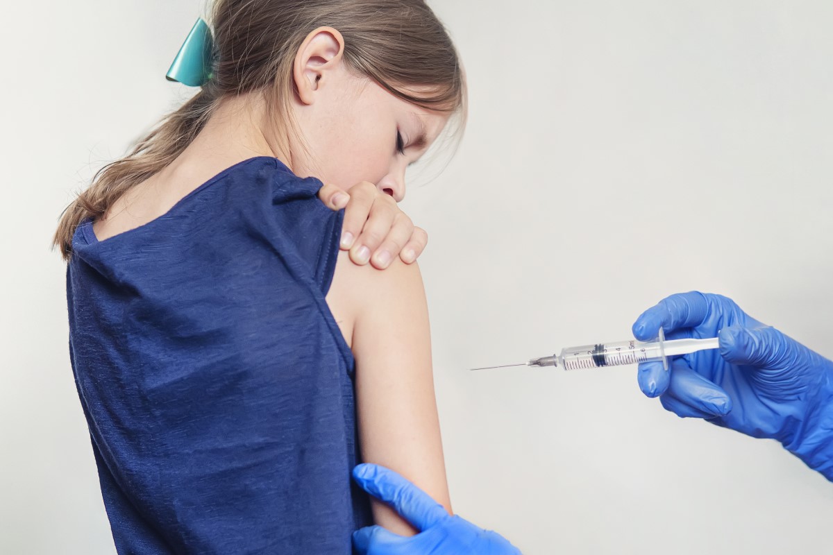 Vaccination av ett barn - flickor - läkaren injicerar vaccinet i axeln