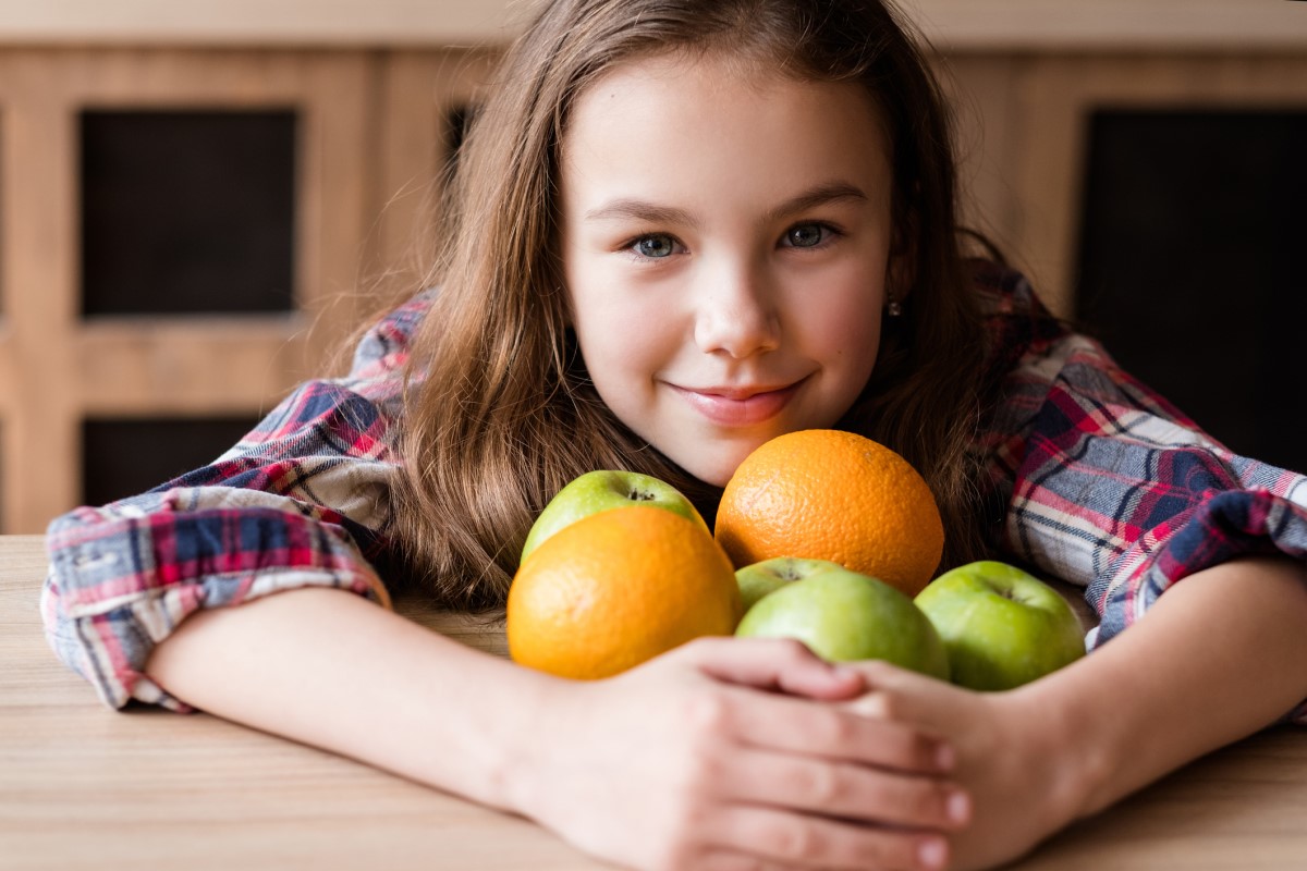 C-vitamin, i frukt, ett barn som håller apelsiner och äpplen i sina armar