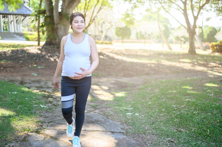 Gravid kvinna promenerar i parken.