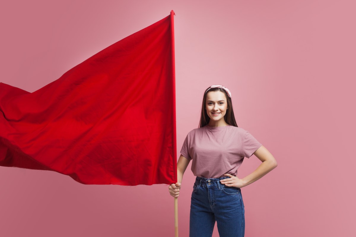 En kvinna håller i en stor röd flagga som en varning.