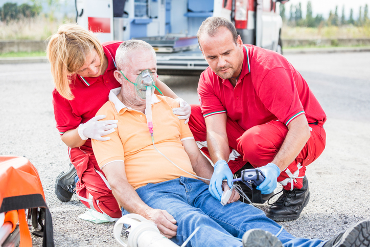 Ambulanspersonal bredvid en kollapsad patient