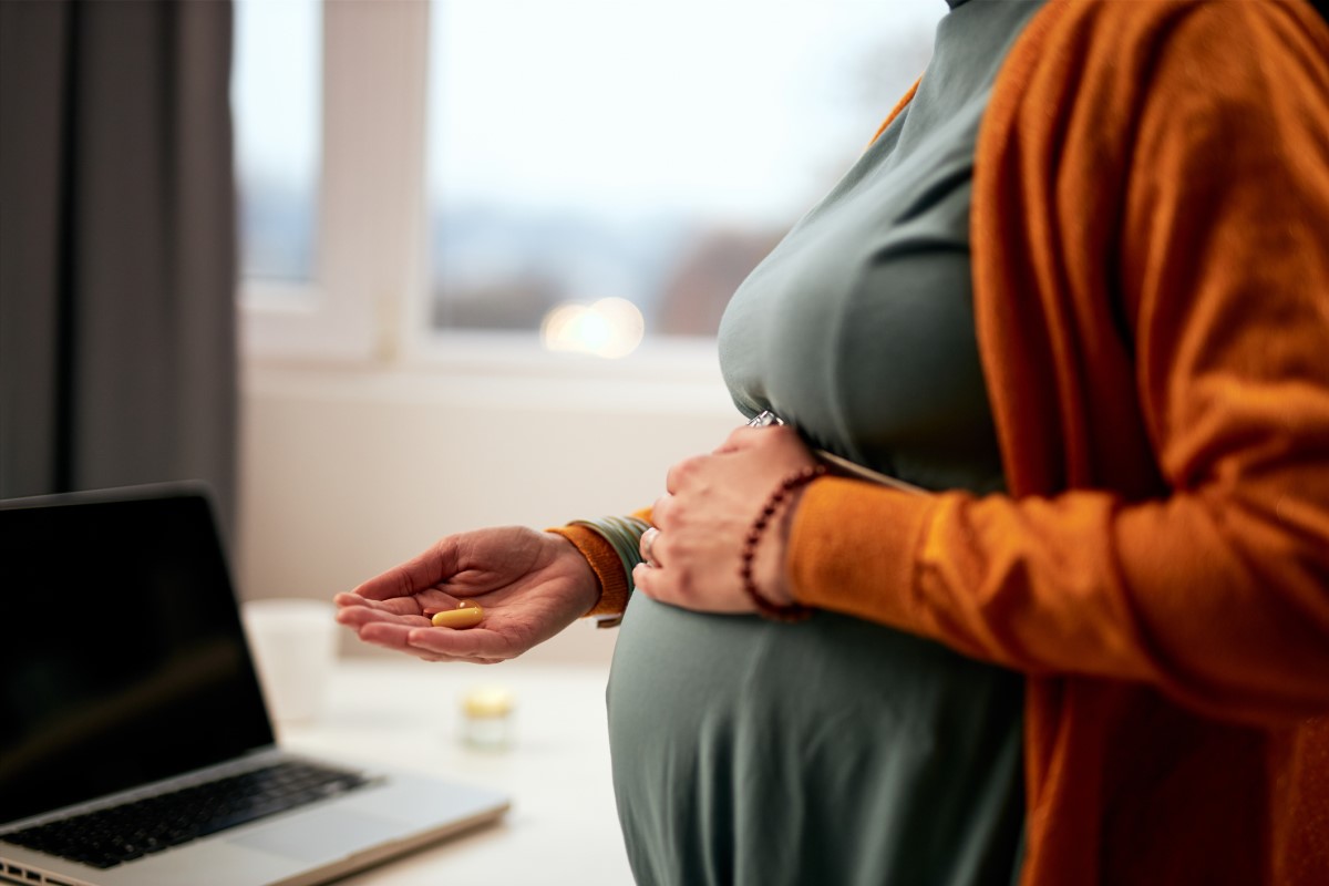 En gravid kvinna håller mediciner i handen och vet inte vilka som är lämpliga ur säkerhetssynpunkt.