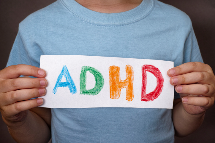 En pojke håller upp en skylt med en färgglad ADHD-skylt på