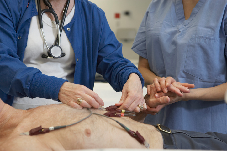 EKG-undersökning av mannen, elektroder på bröstet, två läkare undersöker honom