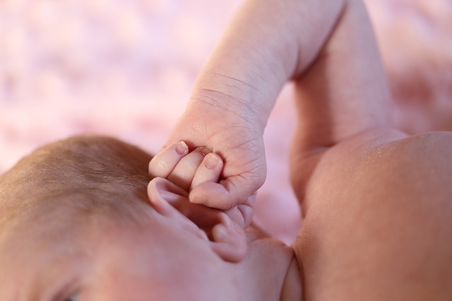 ett litet barn (toddlare) håller sitt öra med handen