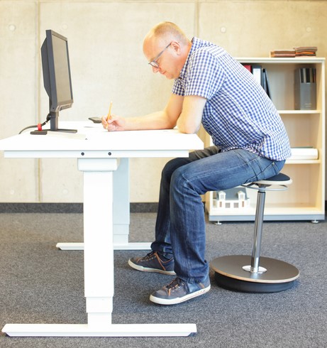 Man sitter vid datorbord, har stillasittande arbete